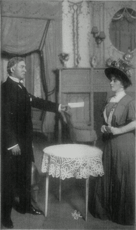 [Photo, from the play,
of Mr. Ryder holding out a cheque to Shirley.]