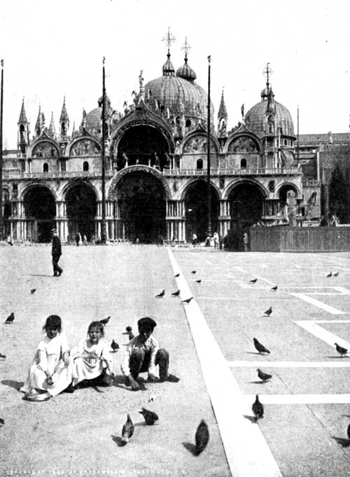 Children feeding Pigeons in the Piazza of St. Mark, Venice. Notice the three flag-poles, and the bronze horses over the central
doorway of the Cathedral.

